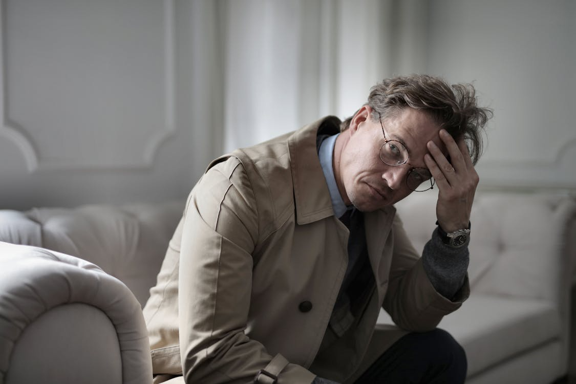 A stressed homeowner sits on a couch reviewing financial concerns after discovering mortgage payment inconsistencies and missing financial records.